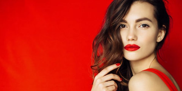 Brown haired woman with red lipstick against red background