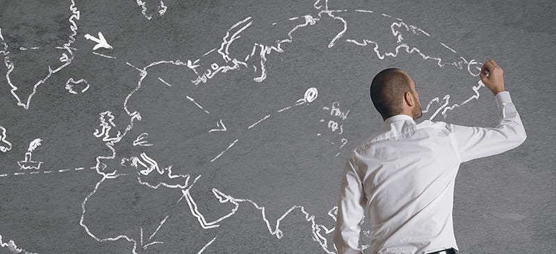 man drawing map of world on a wall